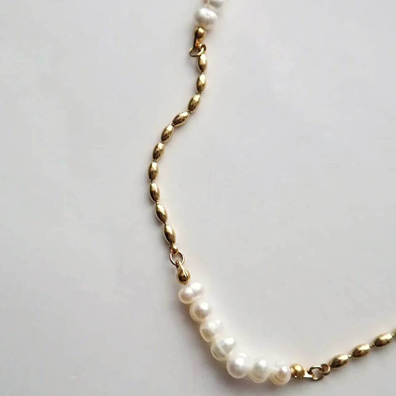 Gold-plated stainless steel links sitting beside the pearls