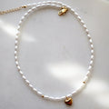 Pearl choker with a small gold heart charm at its centre