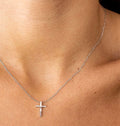 Silver-toned cross pendant hanging from a dainty chain